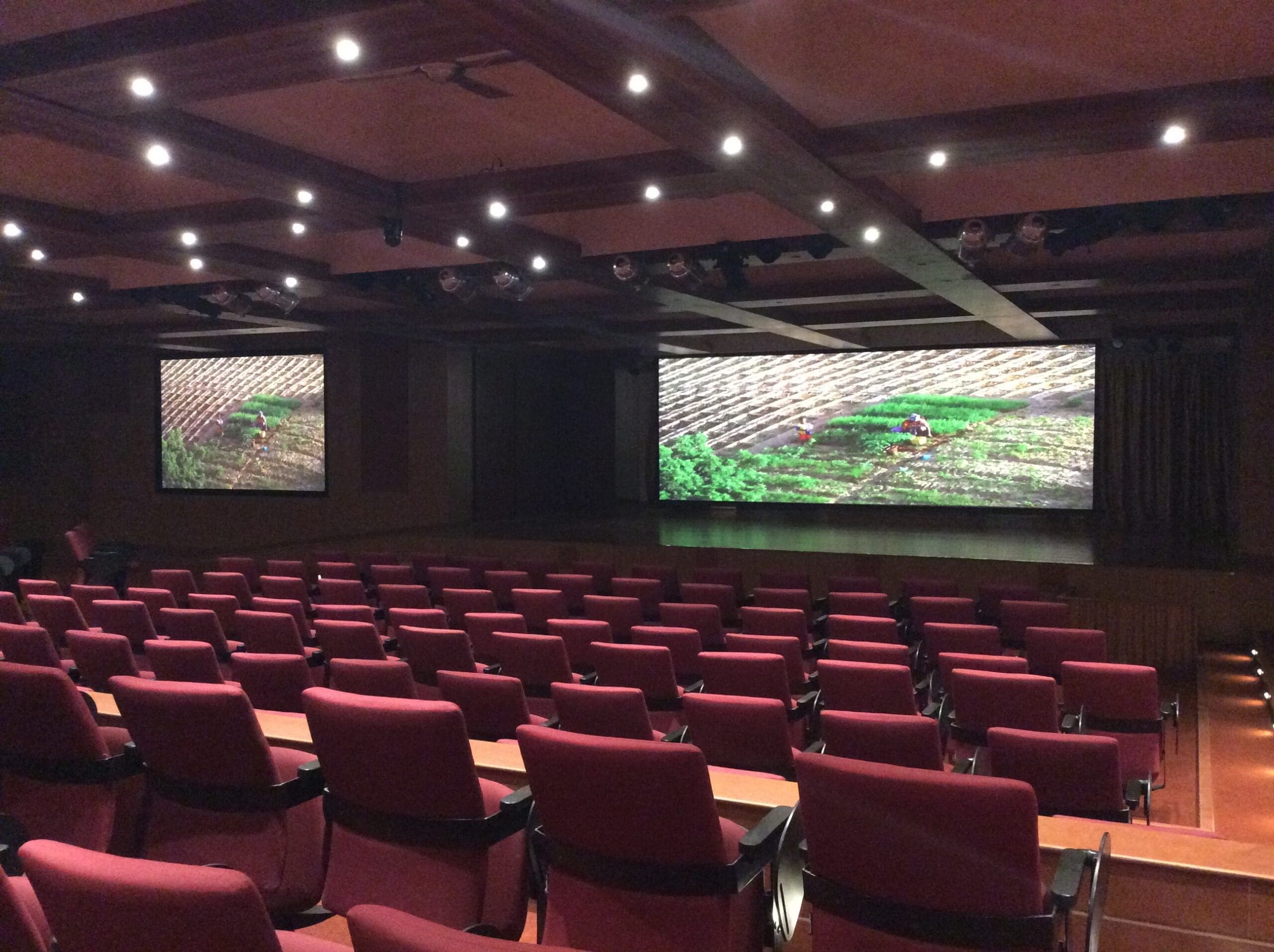 A large auditorium with a multi-screen setup and advanced sound systems for enhanced clarity.